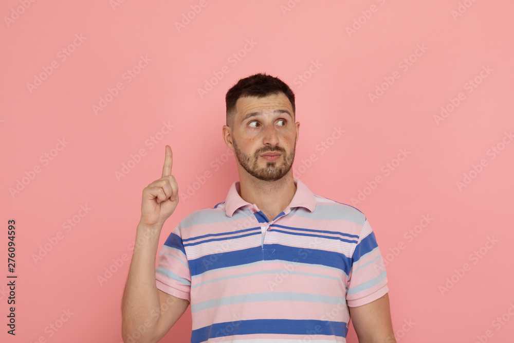 Cheerful bearded man pointing up with finger, over pink background Cheerful bearded man pointing up with finger, over pink background