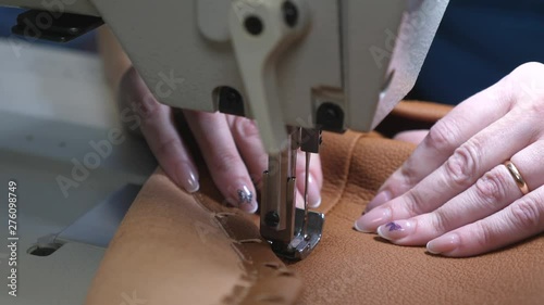 needle of sewing machine in motion. seamstress sews black leather in a sewing workshop. needles of sewing machine quickly moves up and down, closeup. rocess of sewing artificial leather. photo