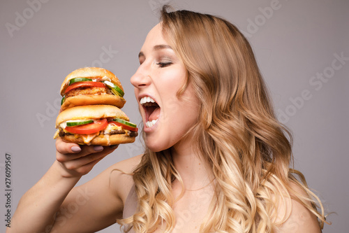 girl with a burger in his hands opened her mouse to eat a big portion of hamburger