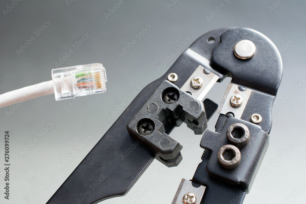 Champper Ethernet patch cable, Ethernet Network Cable Crimp Crimping Crimper Tool, close up gray background Champper Ethernet patch cable, Ethernet Network Cable Crimp Crimping Crimper Tool, close up gray background