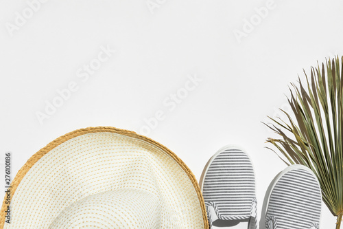 Summer fashion travel vacation concept. Women's female beachwear hat canvas striped shoes dry palm leaf on white background. Bright sunlight harsh shadows. Creative flat lay