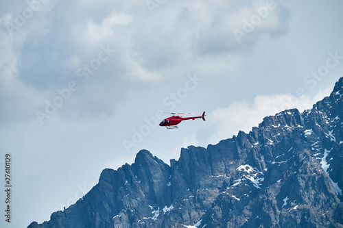 Red helicopter in the sky over the Caucasus Mountains, a beautiful mountain landscape.