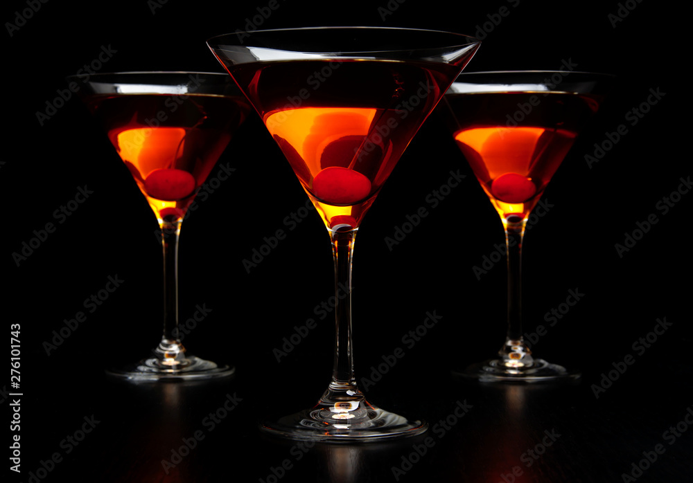 Group of three manhattan cocktails in bar on black table