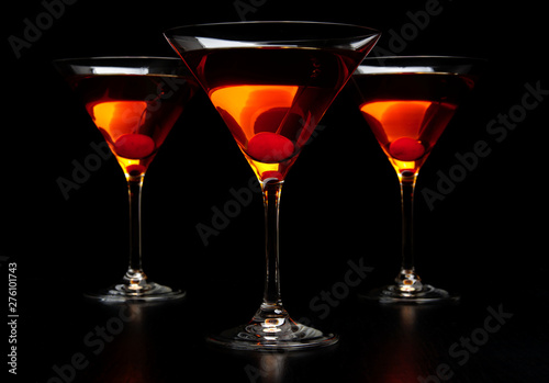 Group of three manhattan cocktails in bar on black table