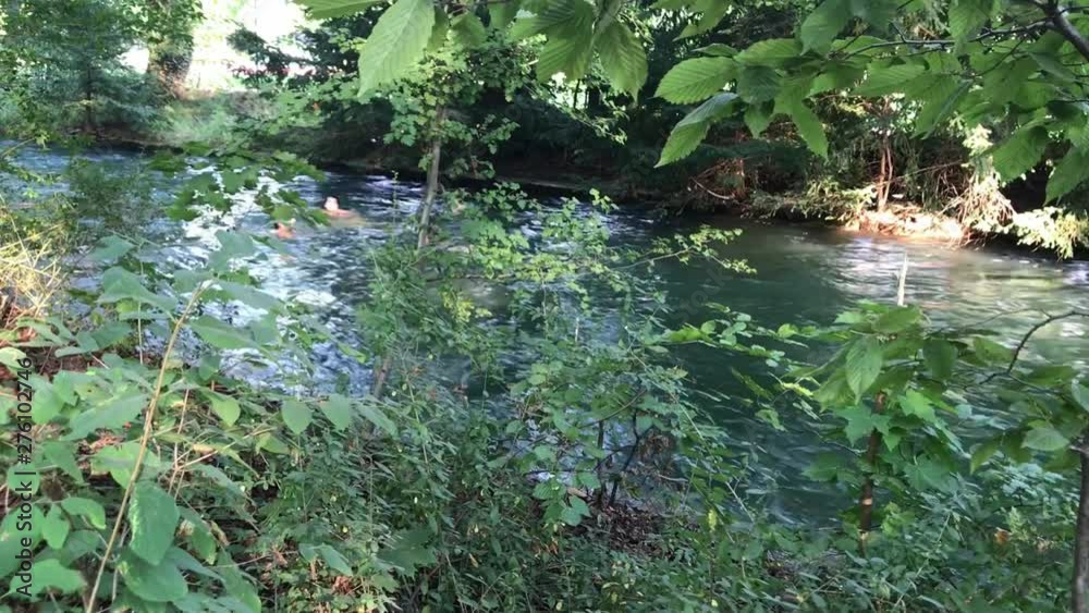 MUNICH, GERMANY - August 2018: Abnormal heat in the city. Citizens have fun swimming in the fast river of the city Park. MUNICH, GERMANY - August 2018: Abnormal heat in the city. Citizens have fun swimming in the fast river of the city Park.