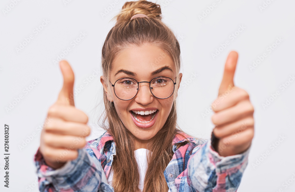 Happy young woman smiling broadly and making thumbs up, showing her support and respect. Pretty Caucasian female making positive gesture. Body language. Good job. Happy young woman smiling broadly and making thumbs up, showing her support and respect. Pretty Caucasian female making positive gesture. Body language. Good job.