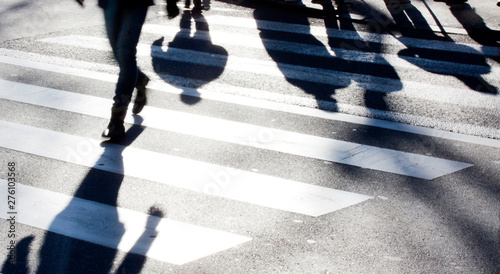 Blurry zebra crossing with pedestrians making long shadows photo