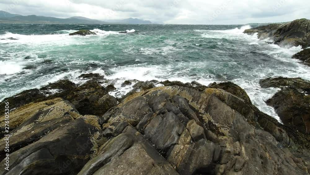 Wide low point of view over a rock of a cold, northern sea scape as grey, white waves hits the shore. Renewable energy with tidal power concept Wide low point of view over a rock of a cold, northern sea scape as grey, white waves hits the shore. Renewable energy with tidal power concept