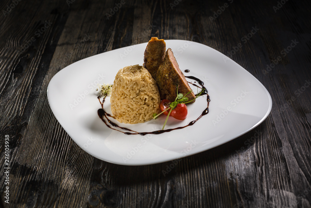 Low key restaurant menu food photo. Delicious fresh rice with meat in white plate on a dark rustic wooden background