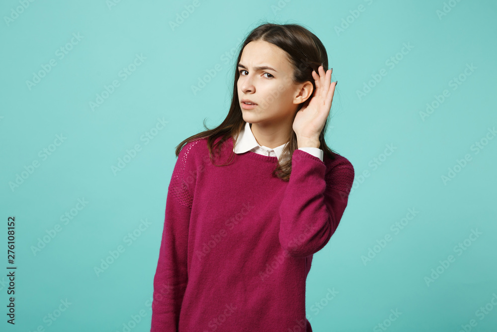 Young fun sad upset perplexed disturb brunette woman girl in red casual clothes posing try to hear you isolated on blue wall background studio portrait. People lifestyle concept. Mock up copy space.