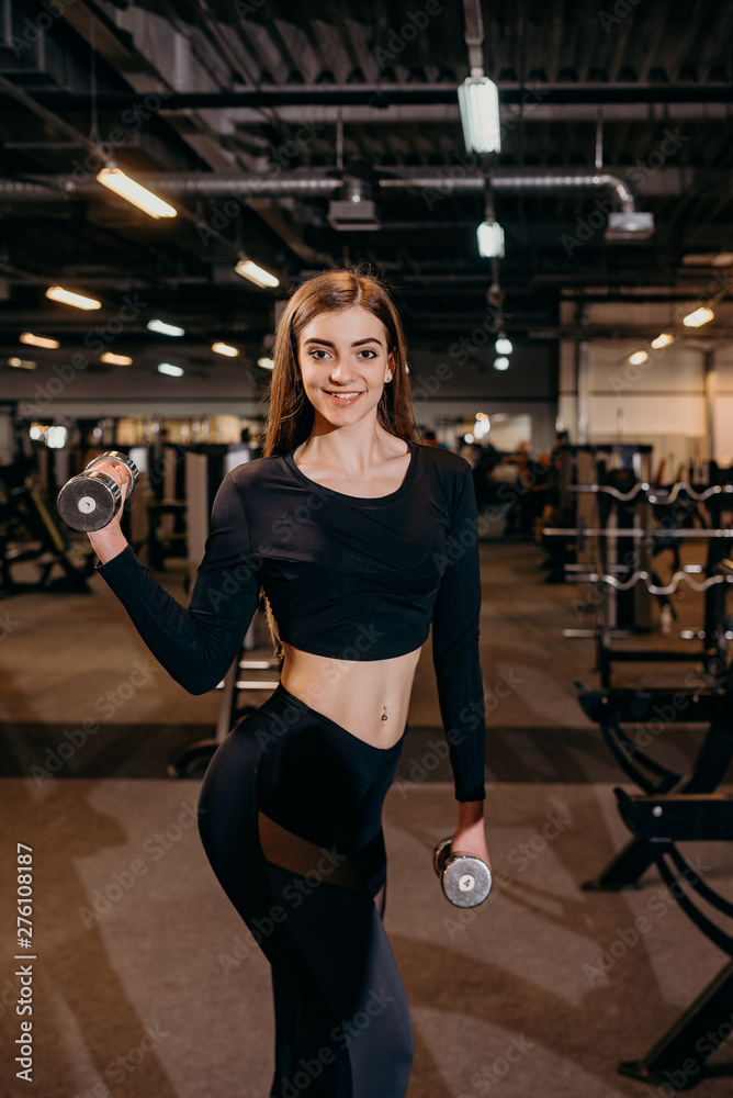 Cute woman doing exercise with dumbbell in gym
