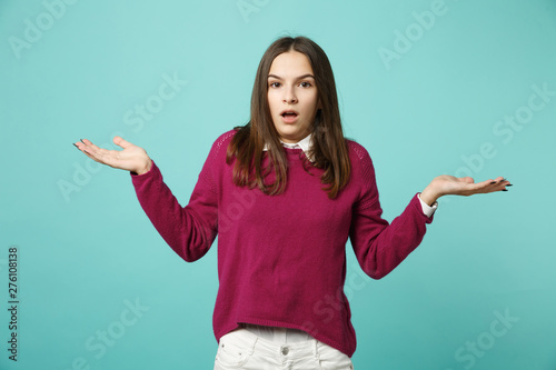 Young fun sad upset perplexed disturb brunette woman girl in red casual clothes posing spreading hands isolated on blue wall background studio portrait. People lifestyle concept. Mock up copy space.