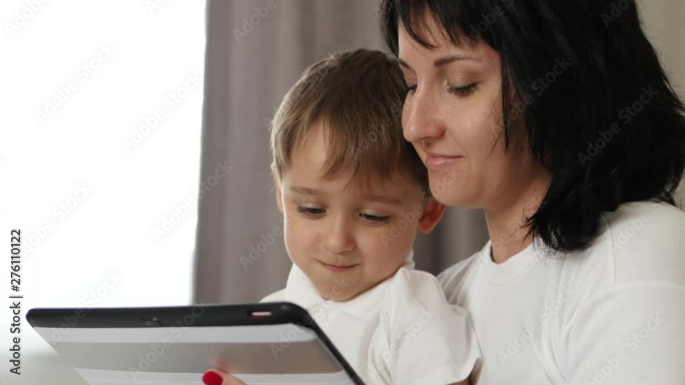 Family portrait. Mother and child looking at the screen of a tablet computer with emotions: joy, happiness, fun. Family portrait. Mother and child looking at the screen of a tablet computer with emotions: joy, happiness, fun.