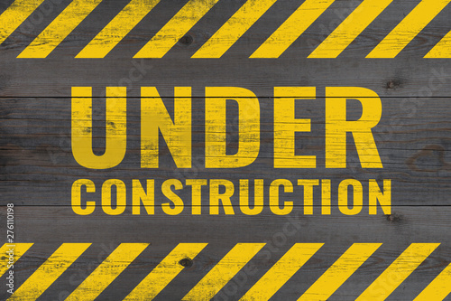 under construction warning message painted on aged wooden planks