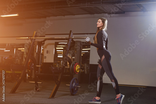 Sports life. Beautiful caucasian woman lifting weights dumbbell in gym.