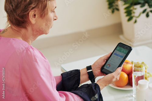 Aged woman checking calorie counter application on smartphone to control her health and diet