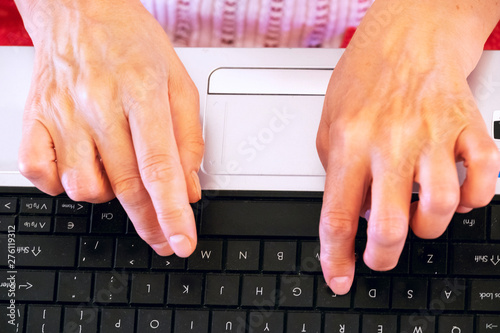 Photos Hands of an old caucasian woman are typing on a laptop keyboard