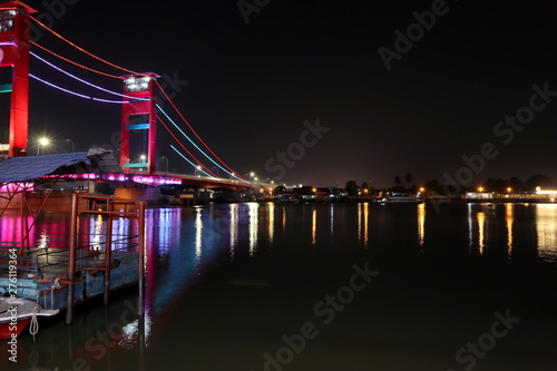 Palembang's Ampera bridge is photographed at night, with natural lighting and slow speed photography techniques.