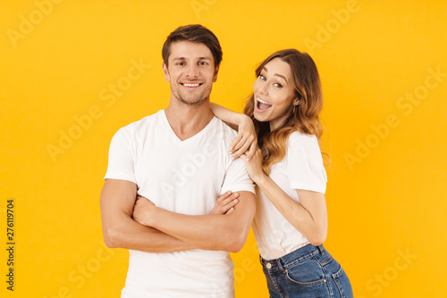 Portrait of joyous couple man and woman in basic t-shirts smiling and hugging together