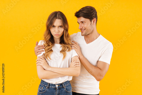Portrait of young man asking for forgiveness displeased woman after fight standing with arms crossed © Drobot Dean