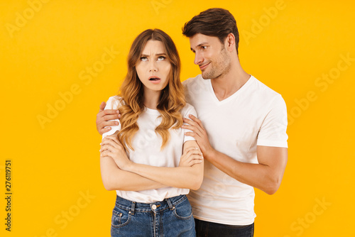 Portrait of handsome man asking for forgiveness irritated woman after fight standing with arms crossed