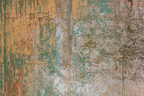 old shabby white yellow concrete wall with cracks, deep scratches and stains of green paint and dirt. rough surface texture