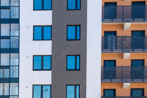  Modern new high-rise building with balconies, windows and multi-colored facade. Front view