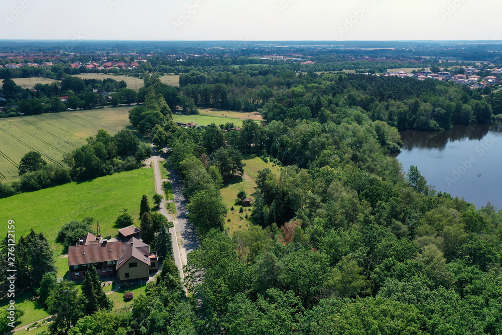 Aerial view from a vertical perspective of a house with big garden at the edge of a forest with a meadow in front of it.