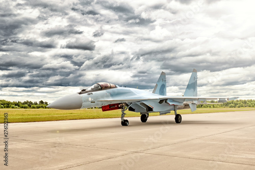 Wallpaper Mural modern military fighter jet airplane in blue and grey camouflage color taxiing to airport runway for take off against dramatic clouds sky landscape background Torontodigital.ca