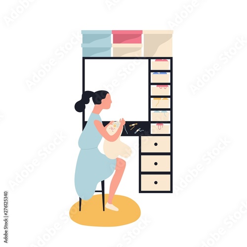 Adorable woman sitting and embroidering or stitching canvas on tambour frame