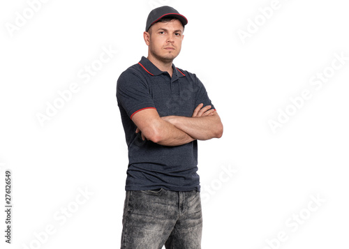 Delivery man in gray t-shirt and cap. Studio portrait of caucasian handsome guy with arms folded and looking on camera. Courier isolated on white background.