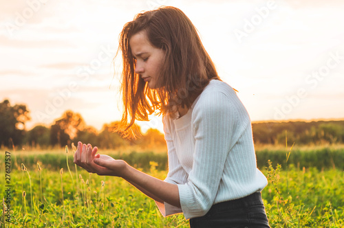 Tela Teenager Girl closed her eyes, praying in a field during beautiful sunset