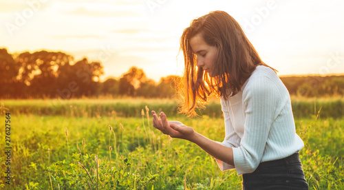 Teenager Girl closed her eyes, praying in a field during beautiful sunset. Hands folded in prayer concept for faith, spirituality and religion. Peace, hope, dreams concept
