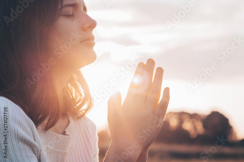 Fotografie, Tablou Teenager Girl closed her eyes, praying in a field during beautiful sunset