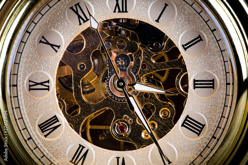 Antique clock on the background of vintage books. Mechanical clockwork on a chain.