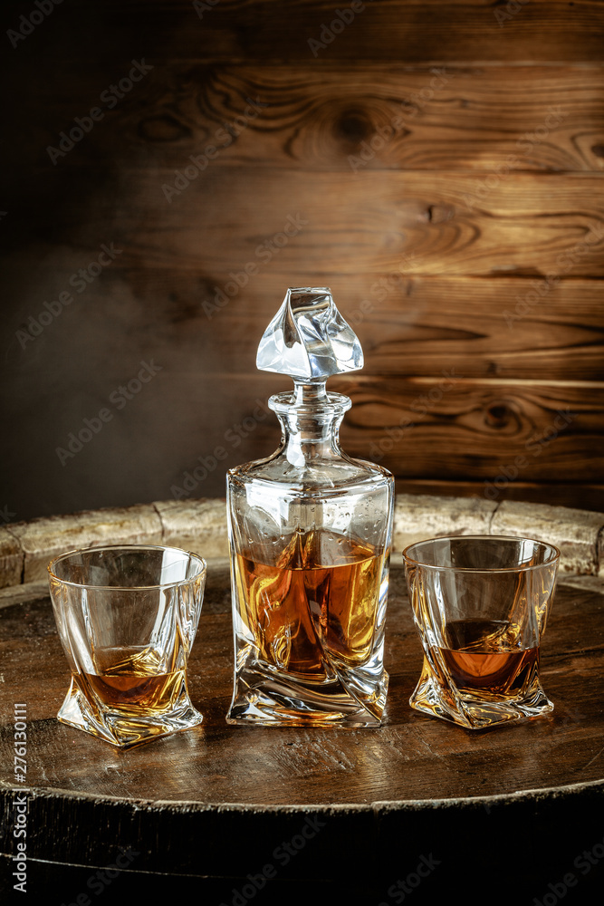 A bottle of cognac and glass on a brown wooden background. Brandy A bottle of cognac and glass on a brown wooden background. Brandy