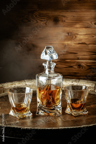 A bottle of cognac and glass on a brown wooden background. Brandy