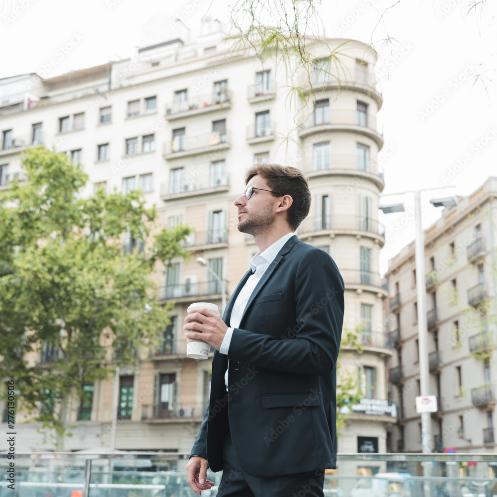 Young businessman standing in front of building holding coffee cup in hand Young businessman standing in front of building holding coffee cup in hand