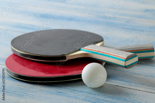 Two ping pong rackets. Table tennis rackets and a ball on a blue wooden table. sport game.