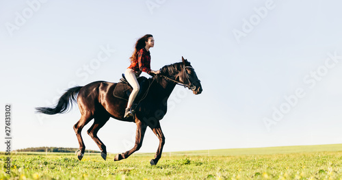 Obraz na plátně Woman riding a horse on a grass field.