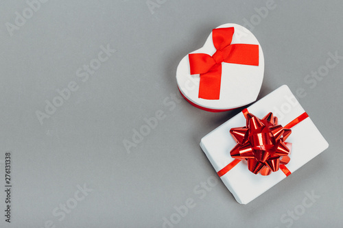 beautiful gift boxes wrapped in paper with a red ribbon and a bow on a gray surface. Top view