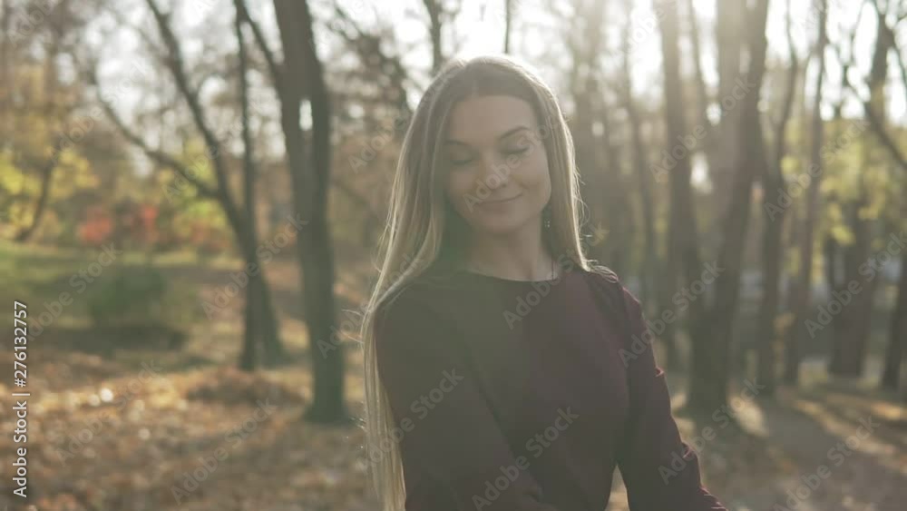 Young woman in autumn park. Portrait of attractive blonde woman at sunset. Sun is shining. Medium shot Young woman in autumn park. Portrait of attractive blonde woman at sunset. Sun is shining. Medium shot