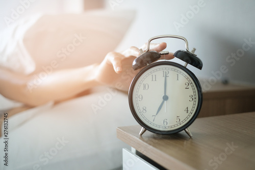 Woman sleep on the bed turns off the alarm clock wake up at the morning, Selective focus.