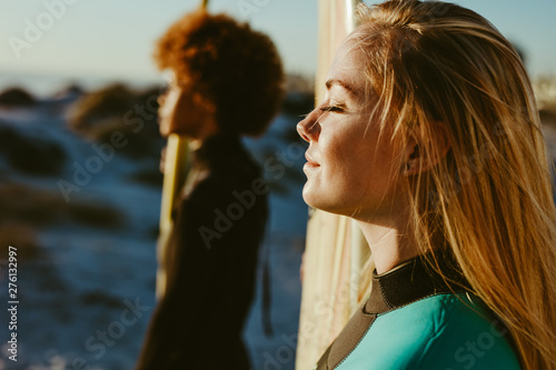 Profiles of two female surfers on beach in sunlight photo