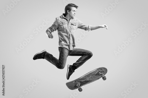 Handsome hipster man in jeans jacket doing the flip on stylish skateboard