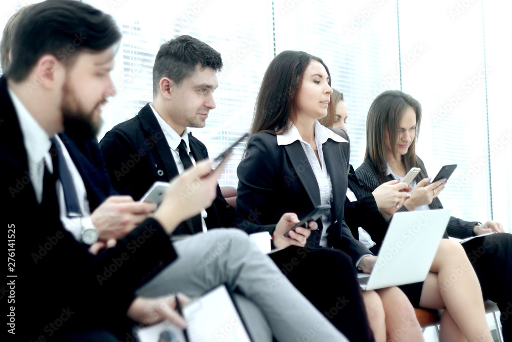 group of young business people use laptops and smartphones while sitting in the office lobby group of young business people use laptops and smartphones while sitting in the office lobby