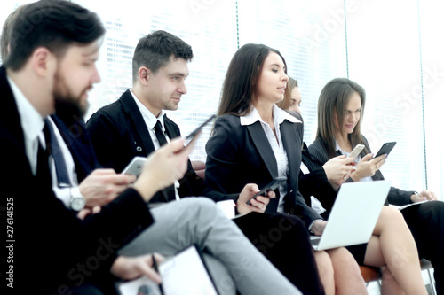 group of young business people use laptops and smartphones while sitting in the office lobby