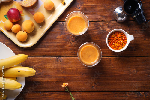 blender  laying at wooden table with fresh fruit smoothie with bananas, sea buckthorn and apricots  . flat lay