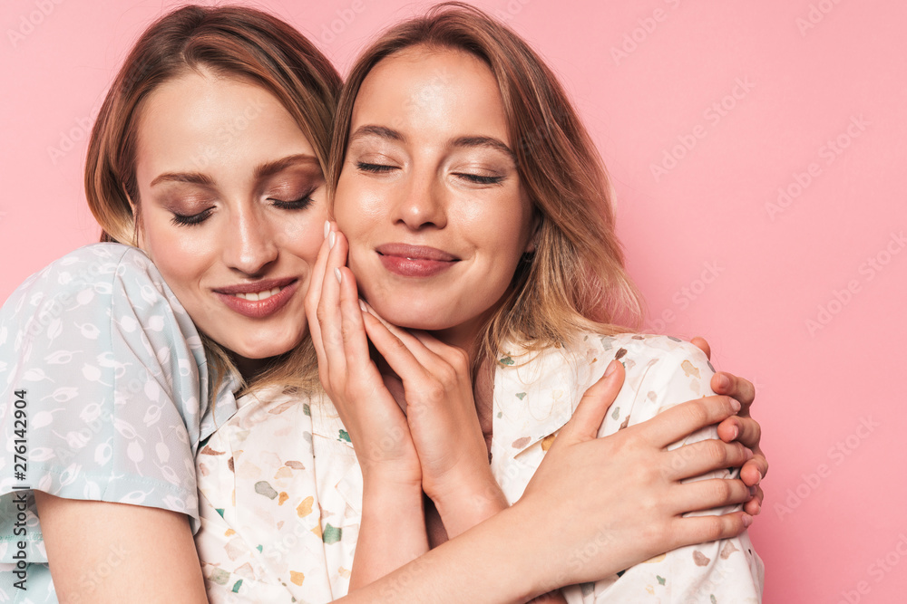 Happy pleased smiling beautiful blondes women friends posing isolated over pink wall background hugging. Happy pleased smiling beautiful blondes women friends posing isolated over pink wall background hugging.