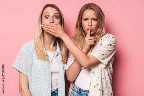 Serious girls women friends sisters isolated over pink wall background covering mouth showing silence gesture.
